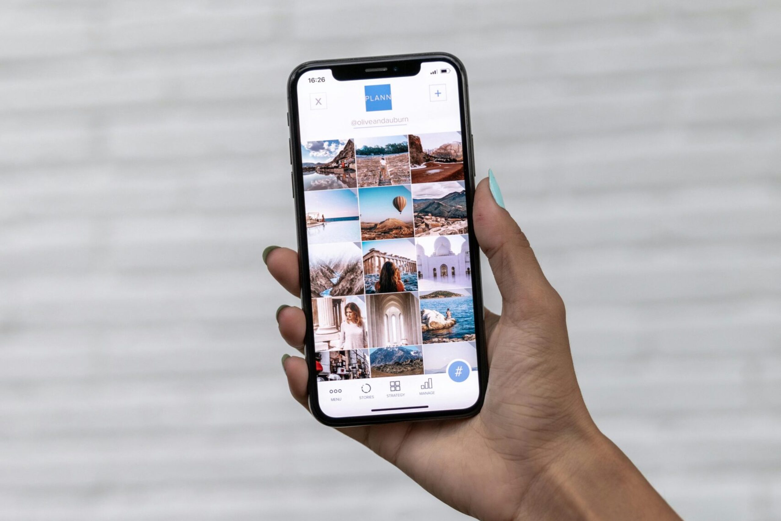A hand holding a smartphone displaying travel photos against a white textured background.